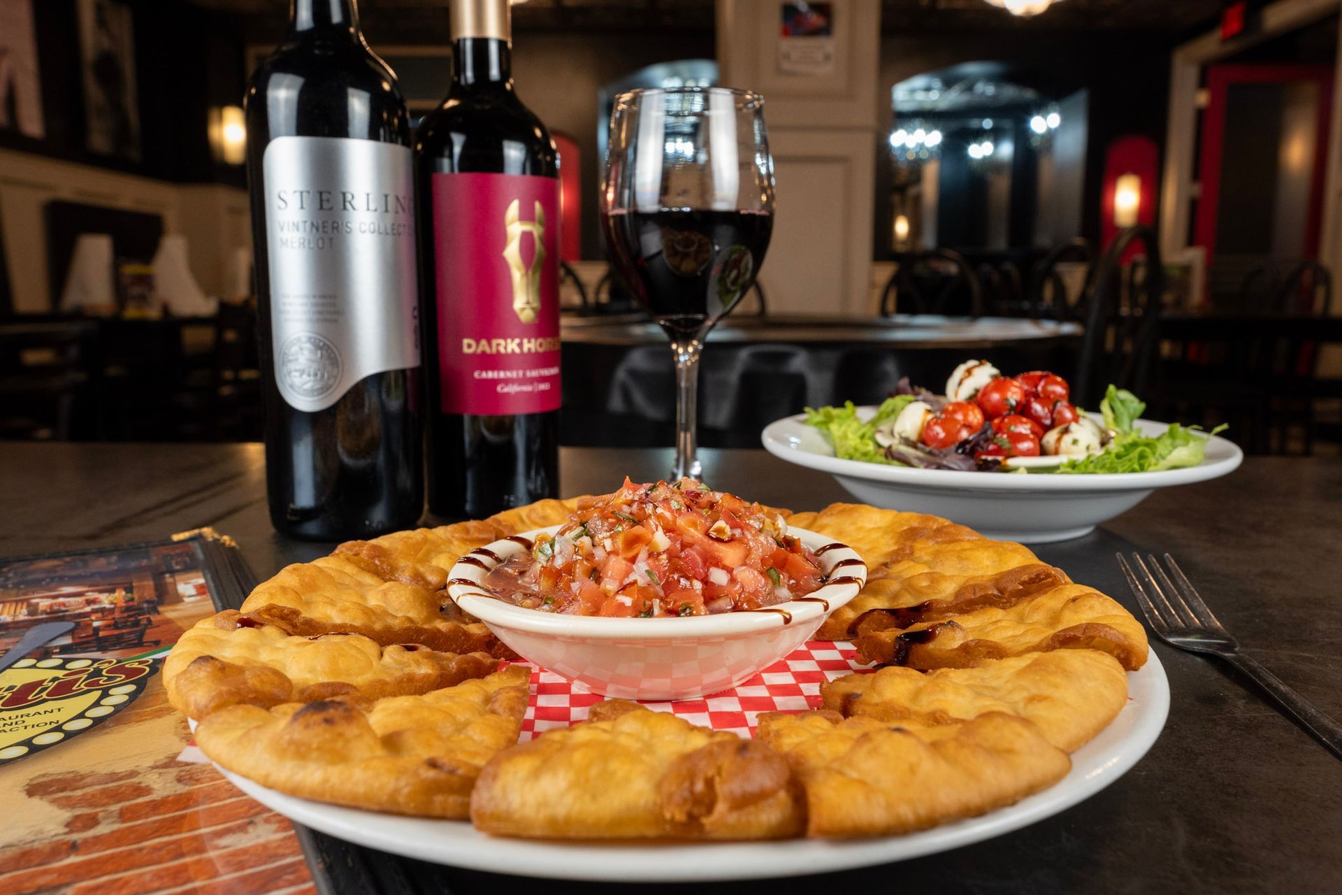 A plate of food and a glass of wine on a table.