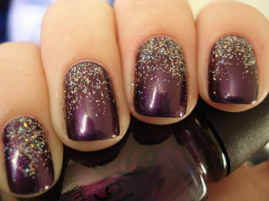 Close-up of fingers with dark purple glitter nail polish holding a matching polish bottle