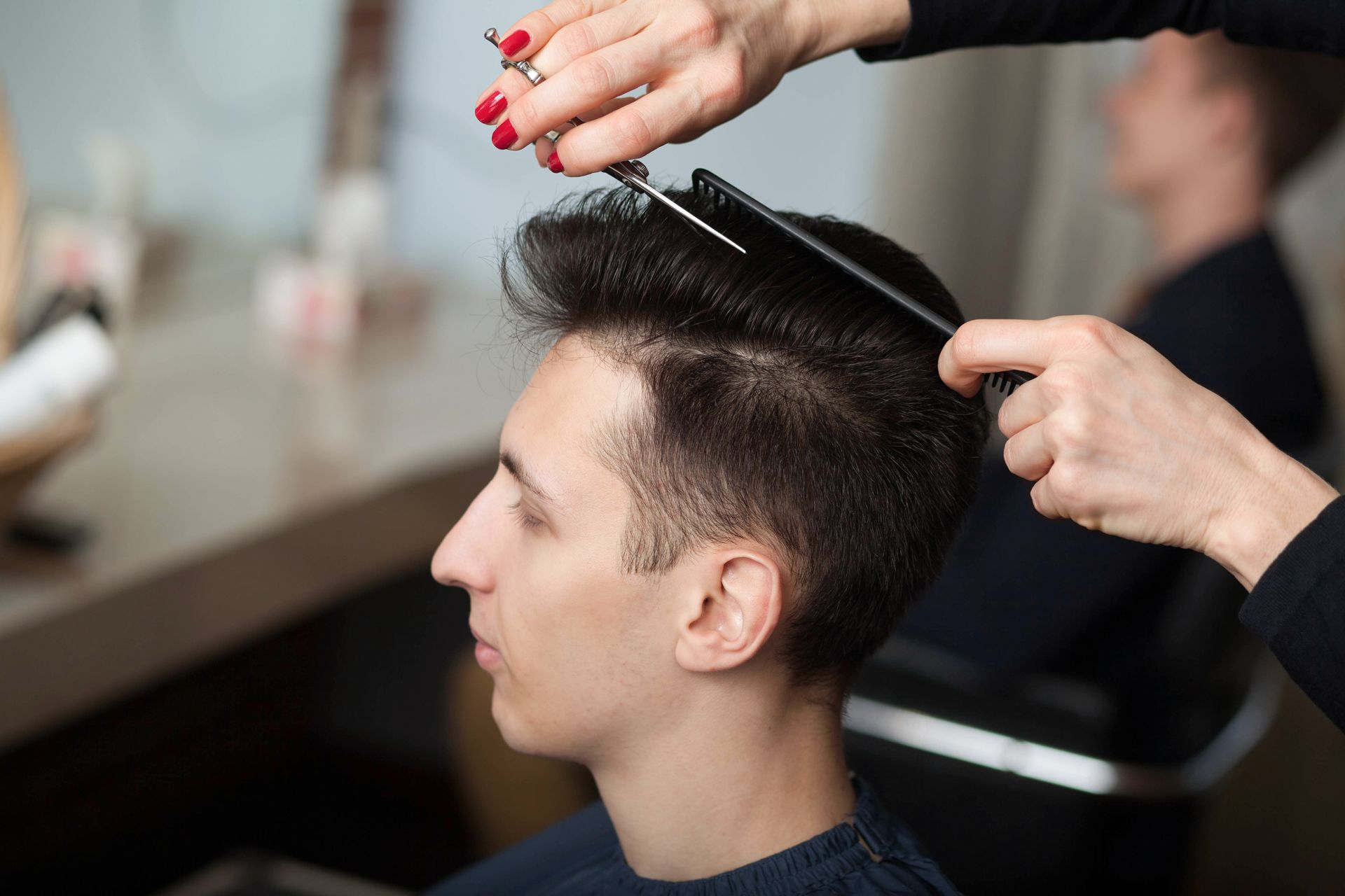 Hairdresser combing a man’s dark hair in a salon