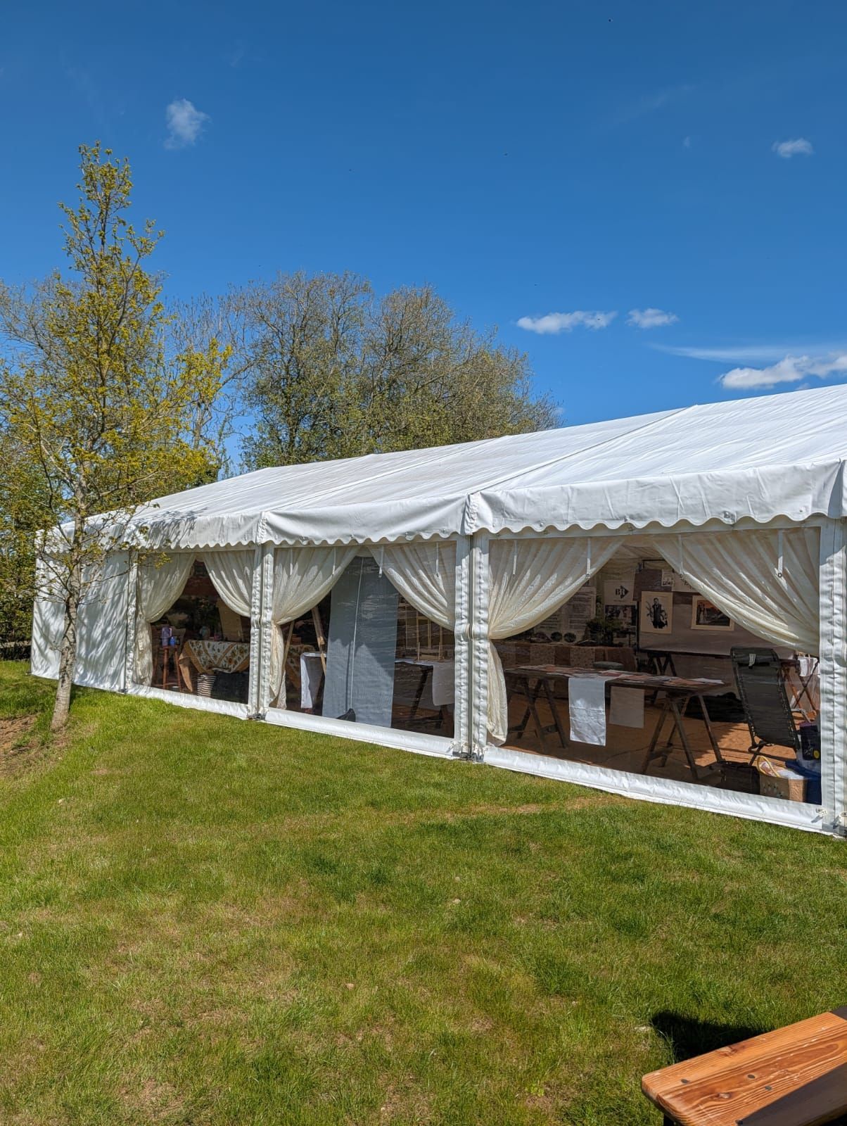 White event tent with draped curtains on a grassy lawn under a blue sky