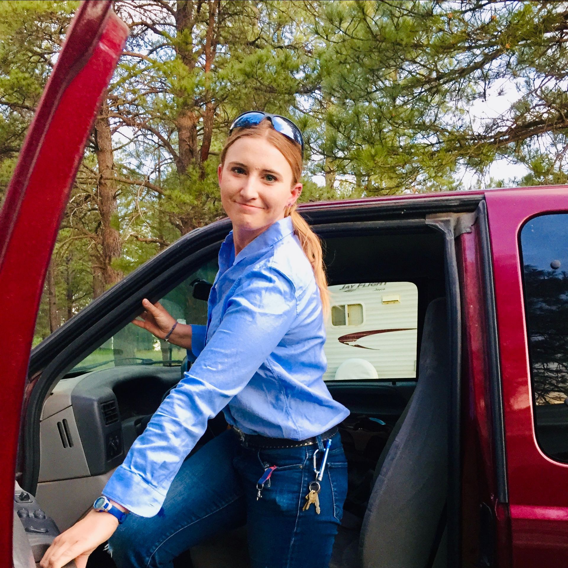 a woman in a blue shirt is getting out of a red truck