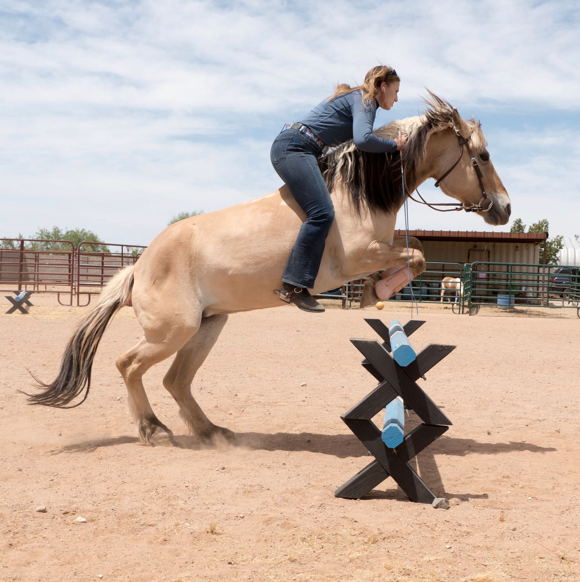 A woman is riding a horse in a dirt field