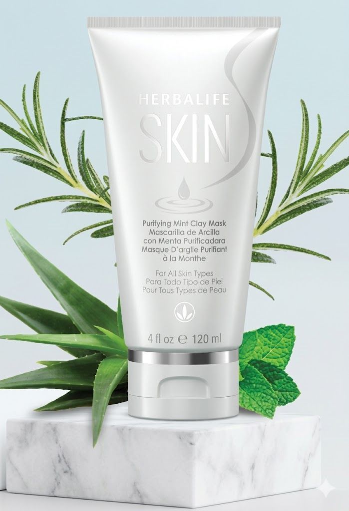 Un tubo de limpiador facial Herbalife reposa sobre un bloque de mármol, enmarcado por ramitas de romero, aloe vera y menta.