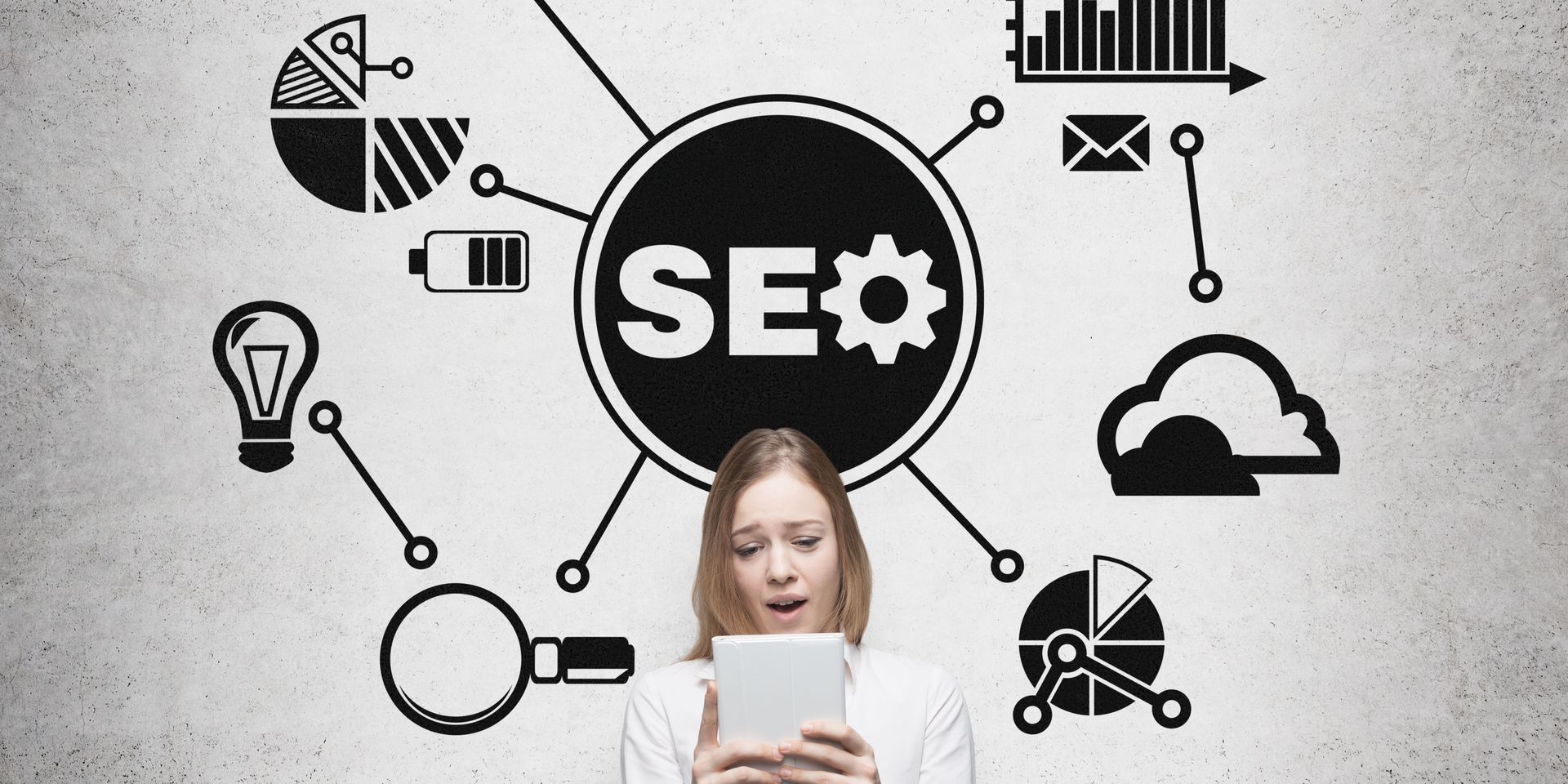 A woman is holding a tablet in front of a drawing of seo icons.