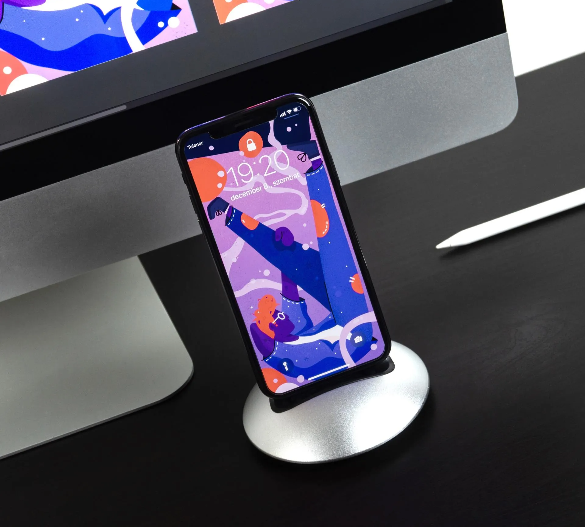 A phone is sitting on a stand next to a computer monitor