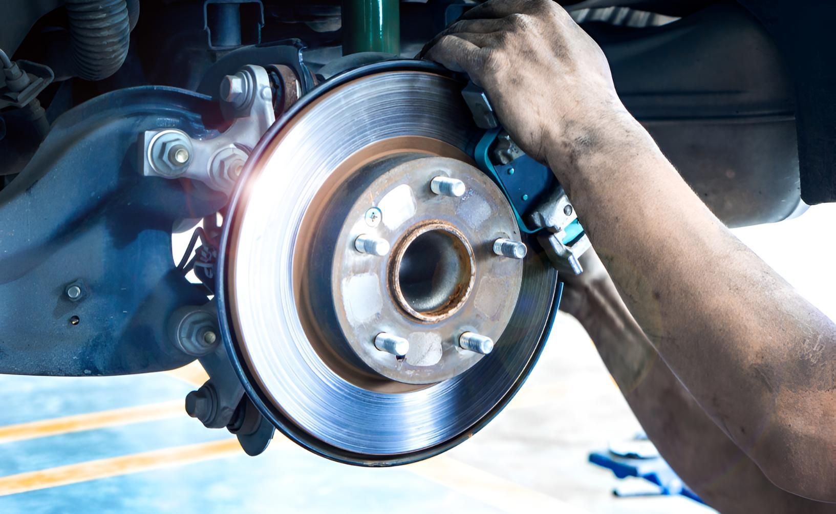A Man Is Fixing A Brake Disc On A Car — Stanger Automatics In Ballina, NSW