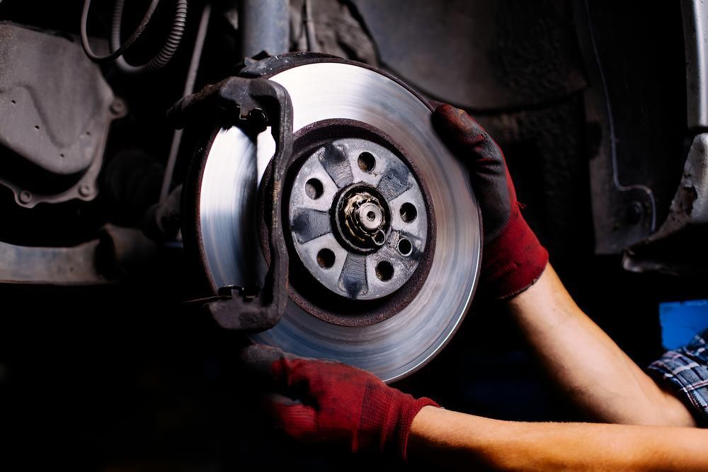 A Person Is Fixing A Brake Disc On A Car — Stanger Automatics In Ballina, NSW