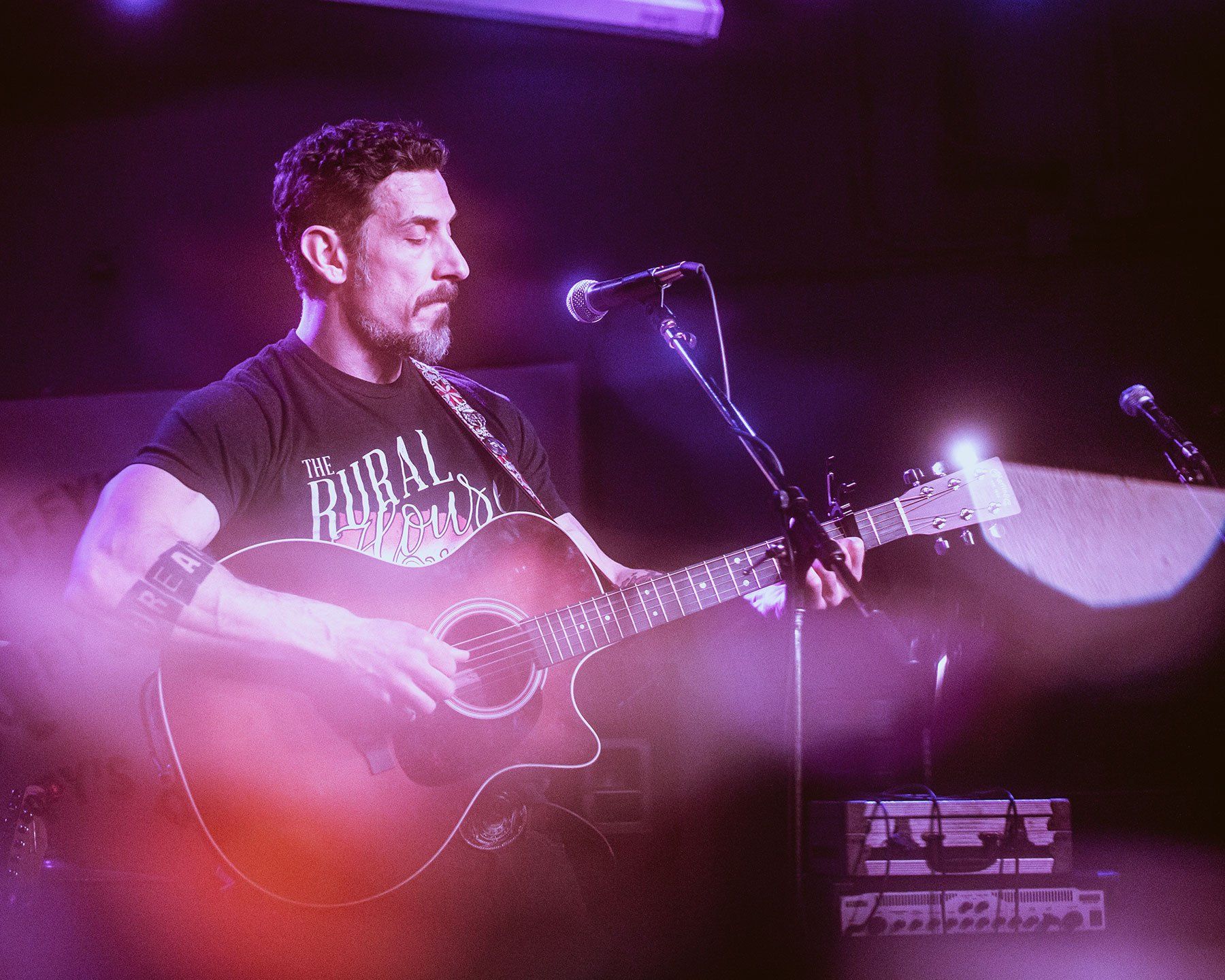Image contains men playing guitar, baseball cap, stage, microphone