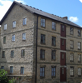A large stone building with many windows and a red door