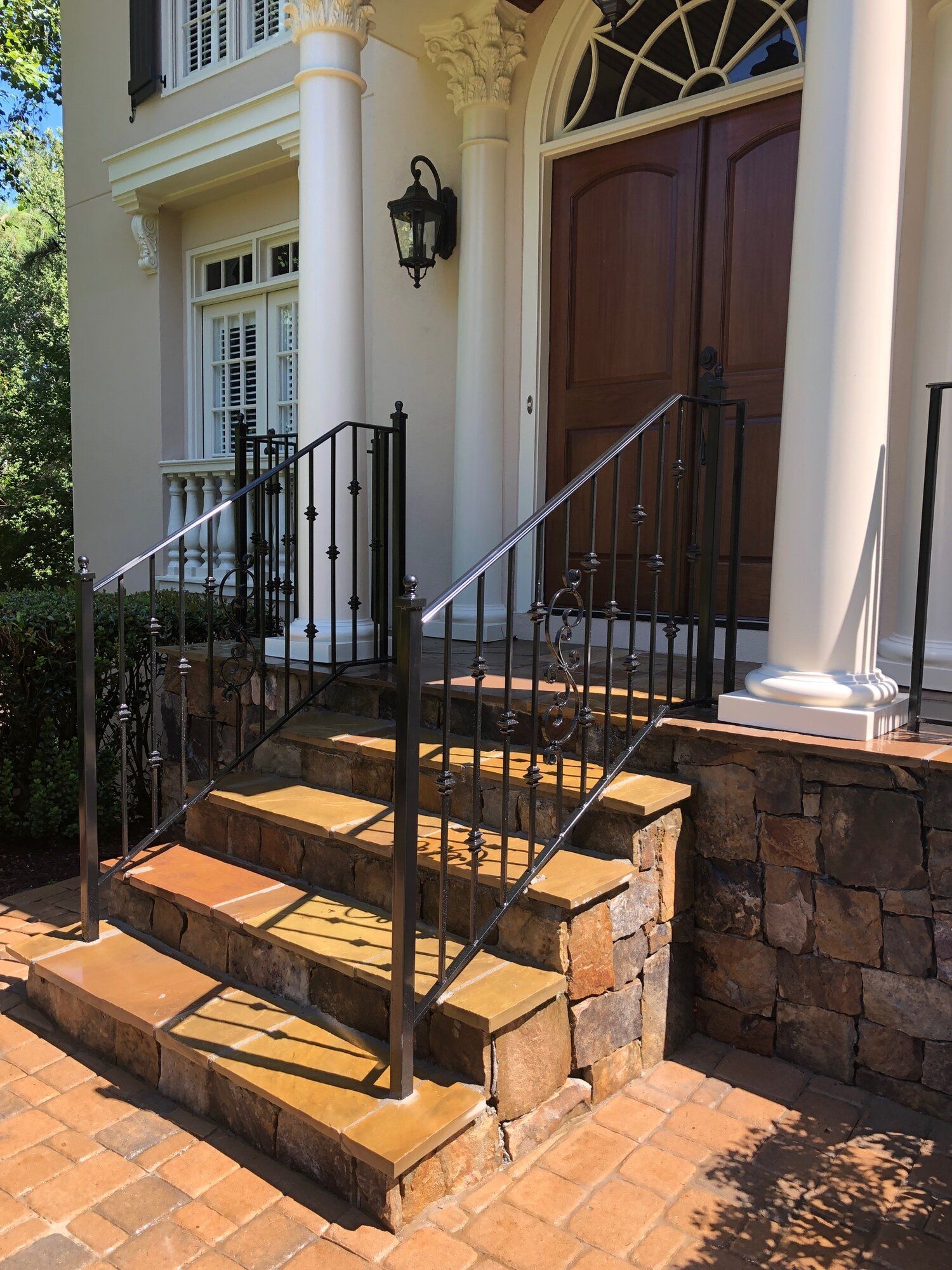 Exterior steps leading to a house with black metal railings and stone accents.