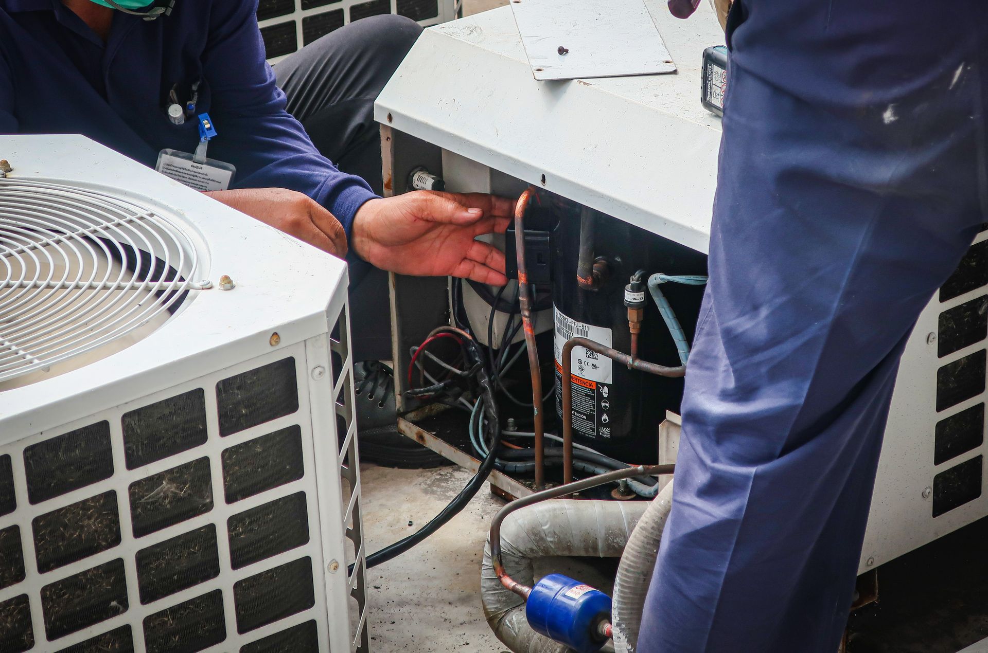Technicians inspecting HVAC units and wiring at an outdoor service site