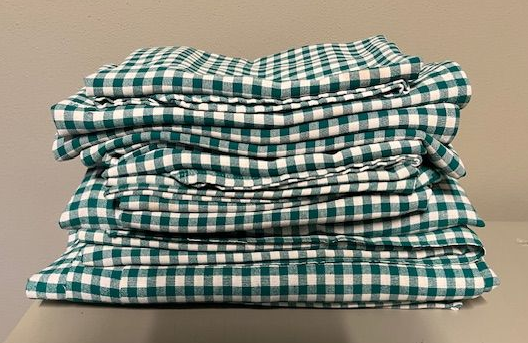 Een stapel groen-wit geruite  tafellakens het waren eerst gordijnen, kreeg een nieuwe bestemming in atelier Biezonder