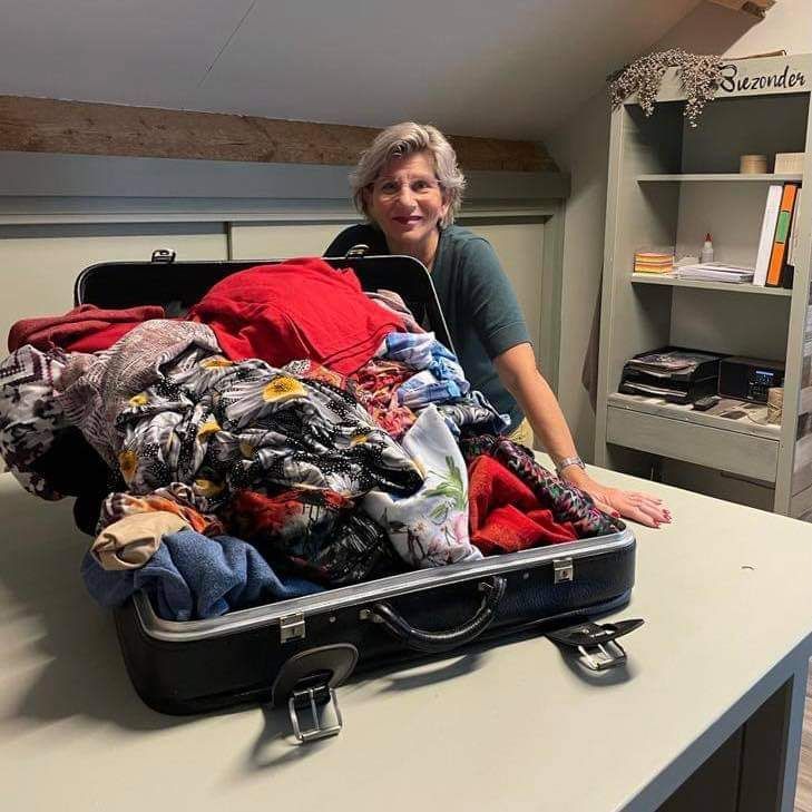 Ell Jans in haar atelier Biezonder achter een koffer met kleding hiervan maakt zij herinneringskussens