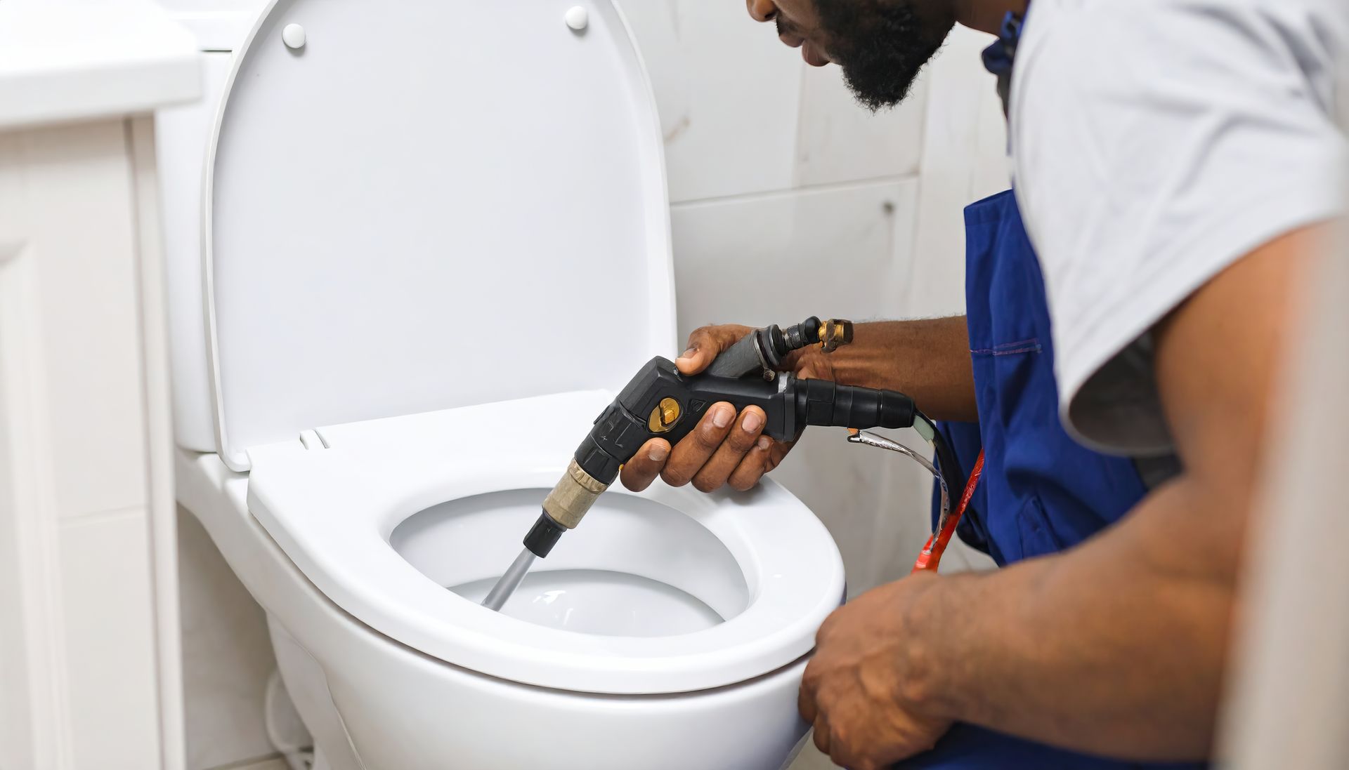 Plumber in red gloves using a wrench on a water filter, plumbing in background.