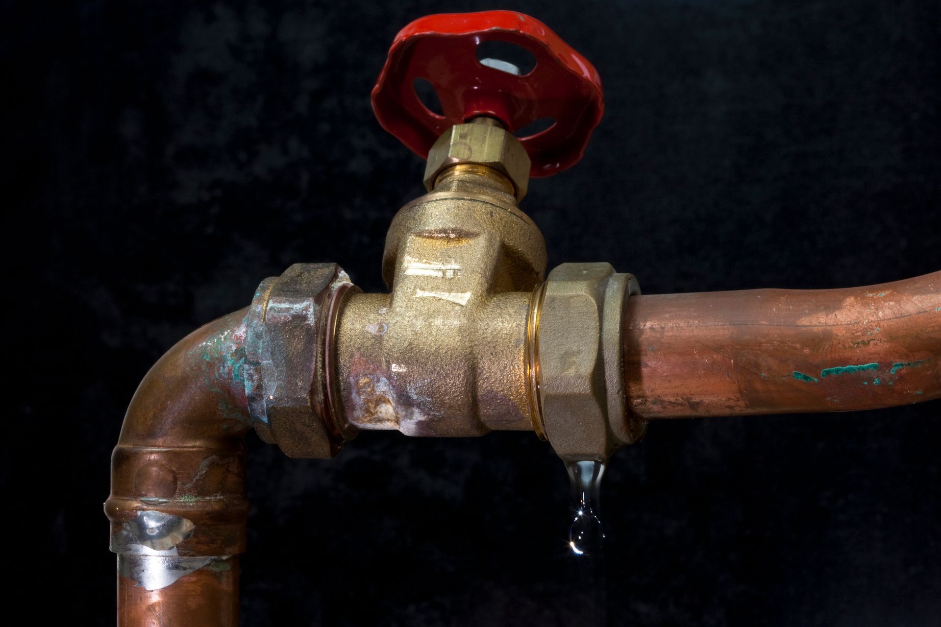 Leaking water faucet, copper pipes, red handle, single water drop.