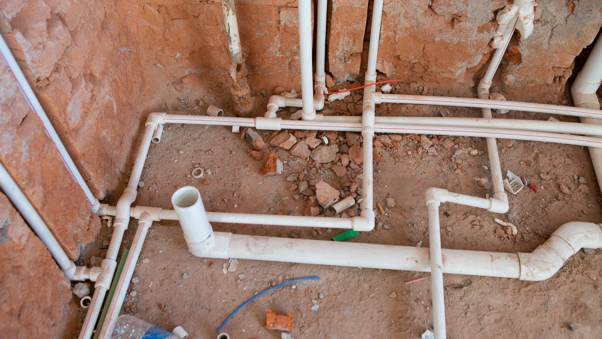White PVC pipes installed in a brick wall, likely for plumbing in a construction setting.