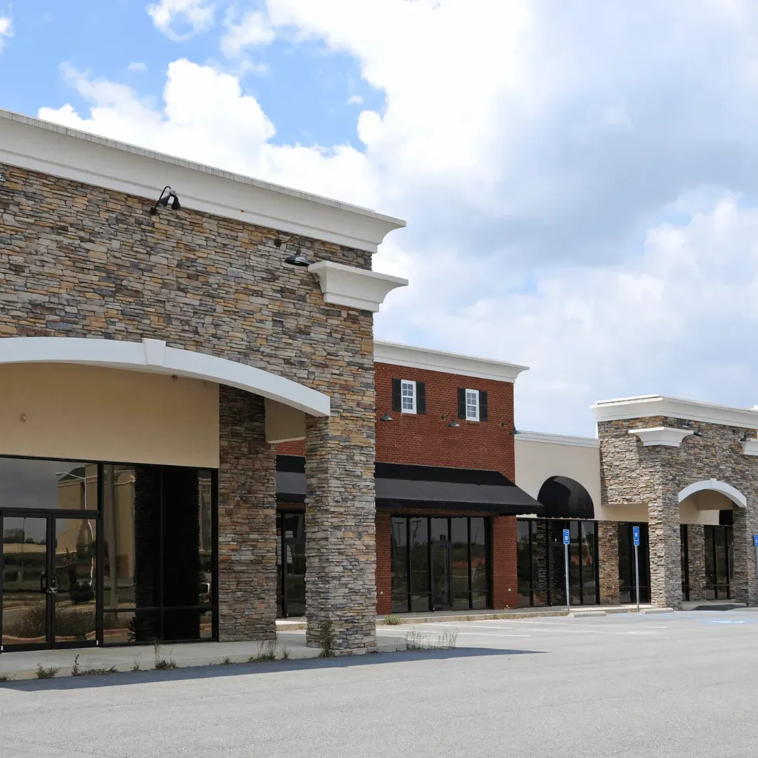 Empty retail storefronts with stone and brick facades under a cloudy sky. Empty retail storefronts with stone and brick facades under a cloudy sky.