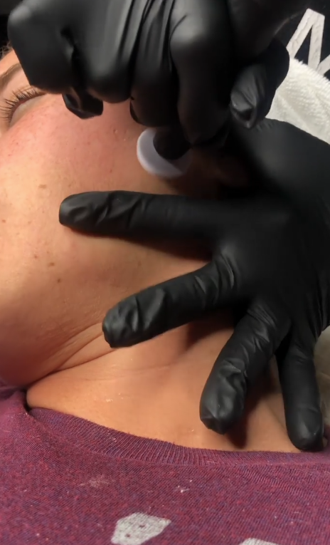 Person in gloves examines a mannequin face during a beauty or training session
