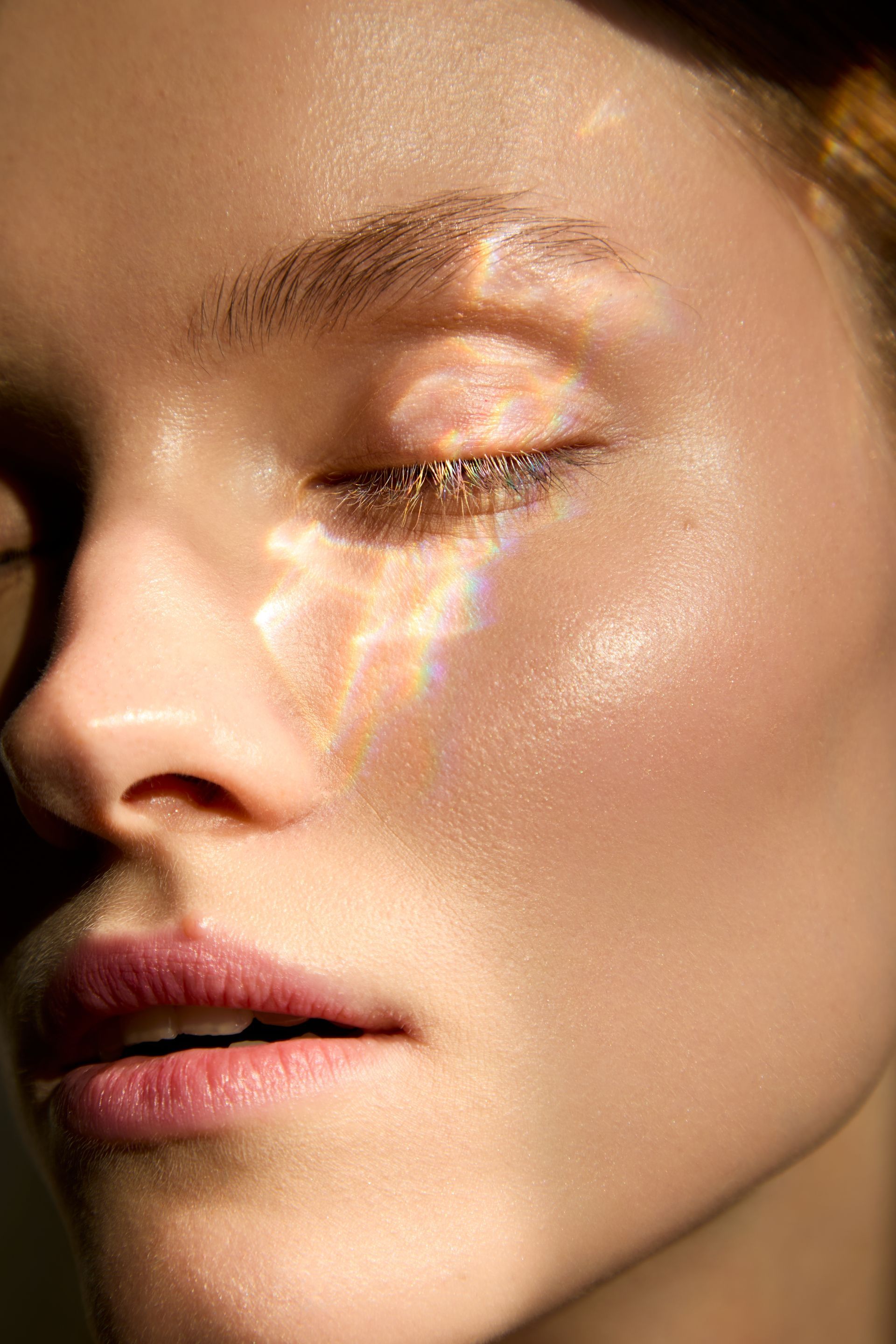 Close-up of a face with eyes closed, warm sunlight highlighting the cheek and nose.