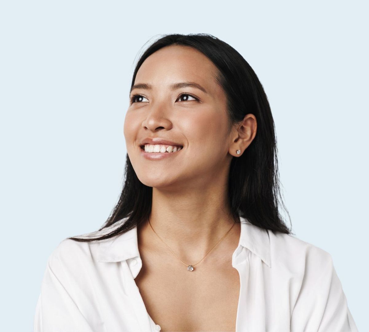 A woman in a white shirt is smiling and looking up.