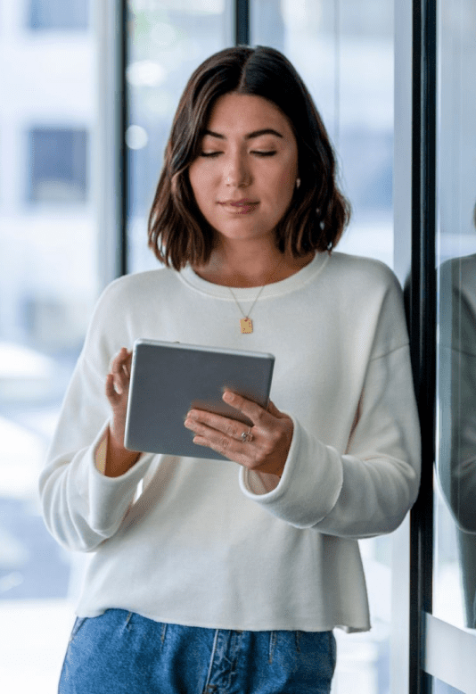 A woman in a white sweater is using a tablet computer.