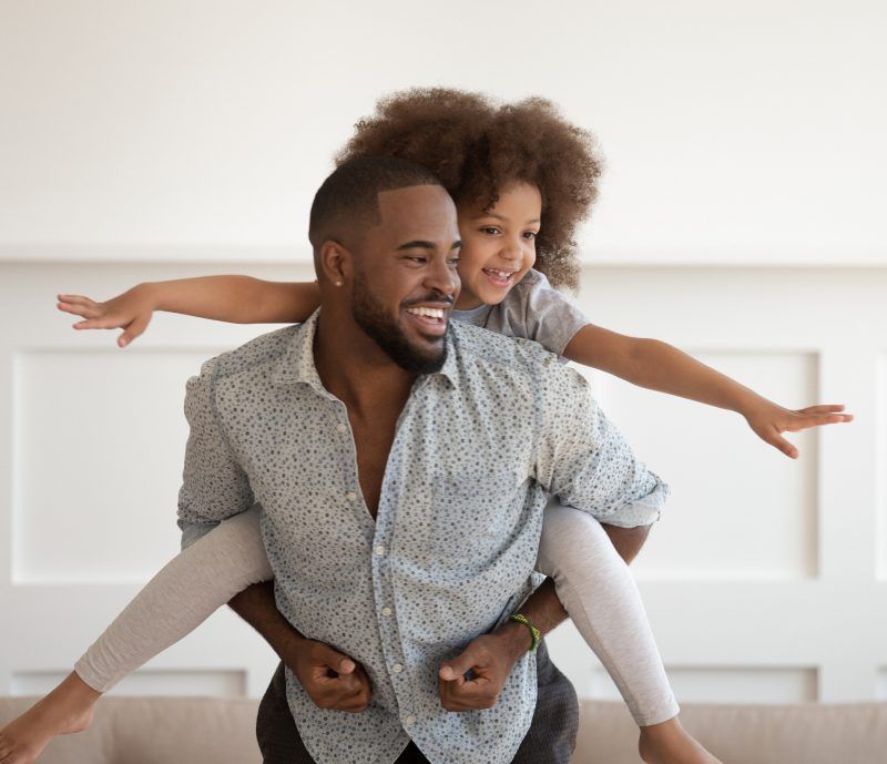 A man is carrying a little girl on his shoulders.