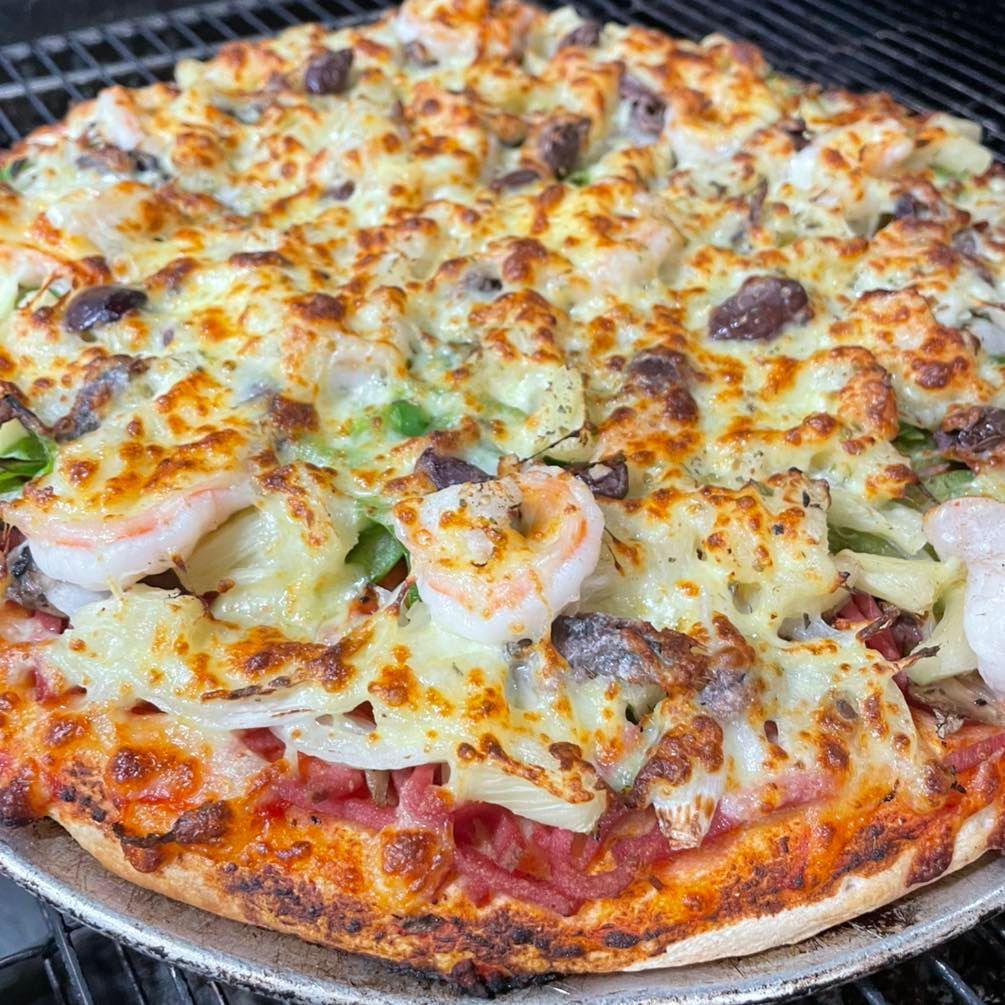 Cheesy seafood pizza with shrimp and mushrooms on a grill rack
