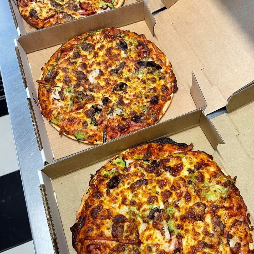 A Man And A Woman Are Preparing Pizza Dough In A Kitchen — Bel-Air Pizza In Port Macquarie, NSW