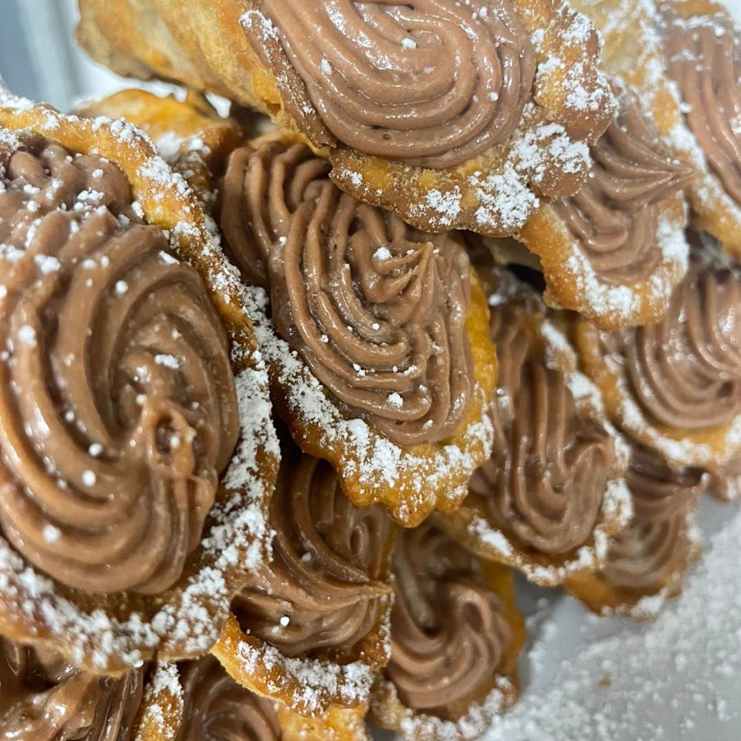 Close-up of powdered sugar pastries topped with swirled chocolate cream filling.