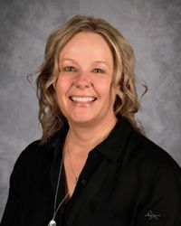 Smiling woman in a black blouse against a gray studio backdrop
