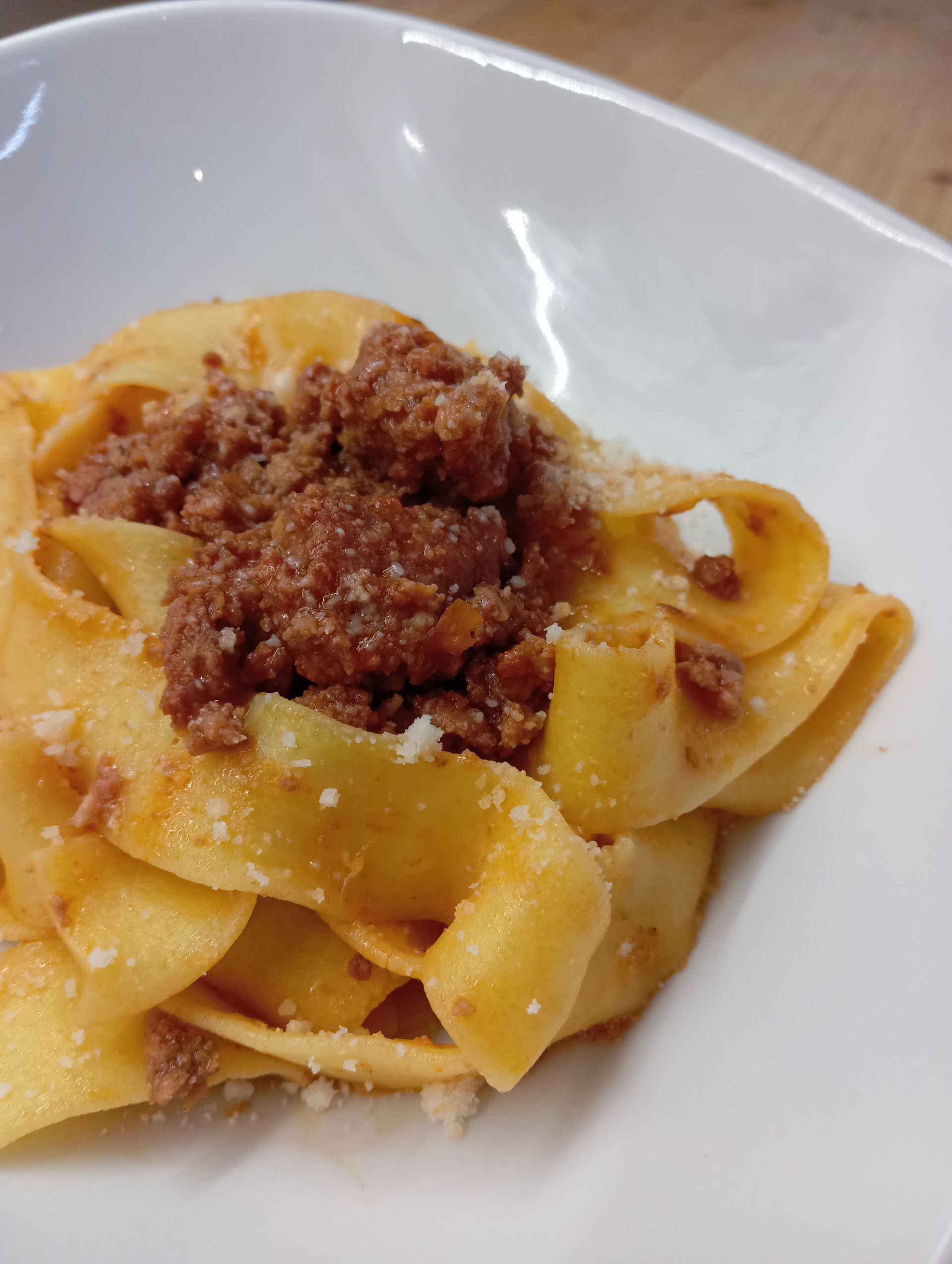 Pappardelle condite con ragù di carne in una ciotola bianca