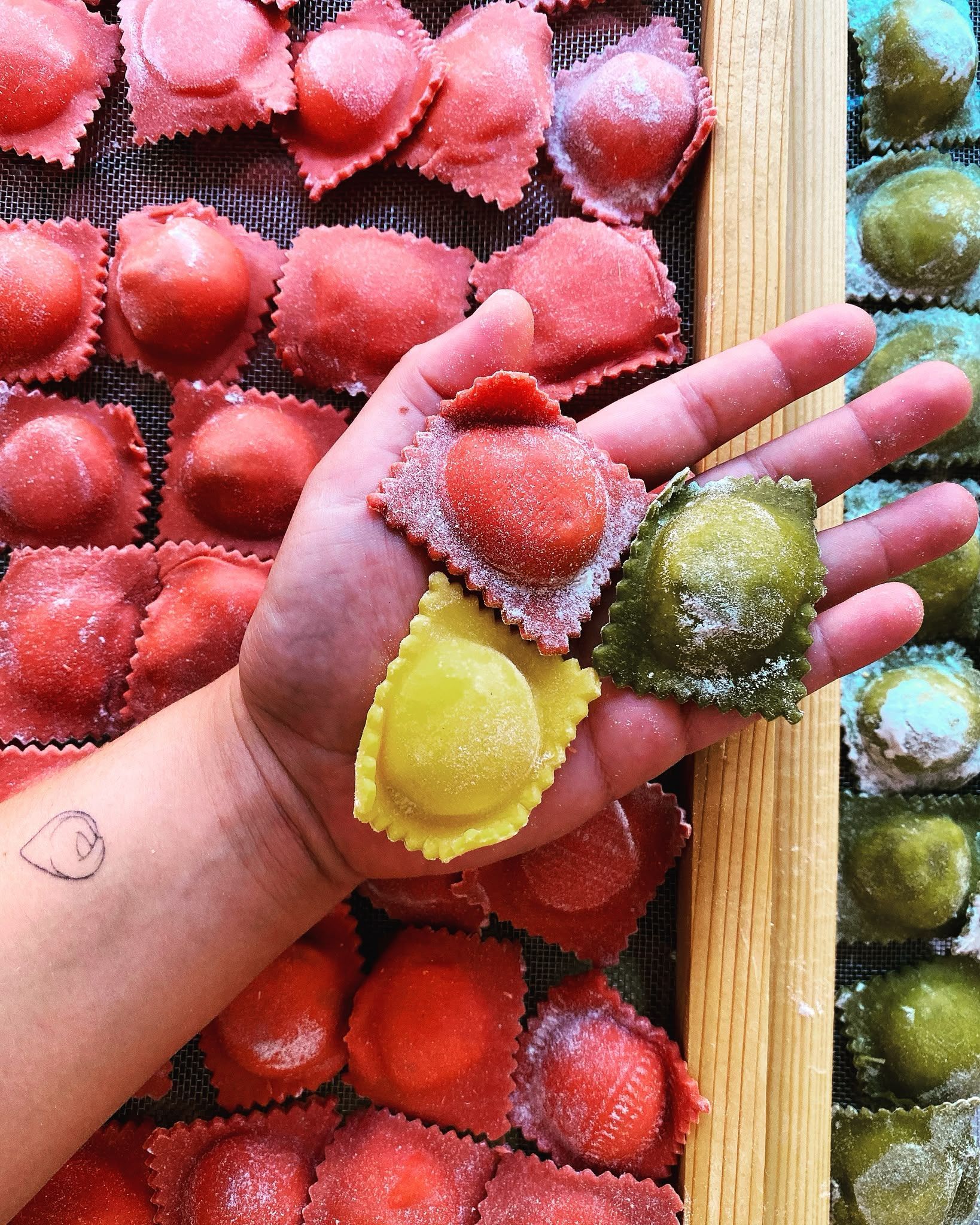 Mano che regge caramelle alla frutta colorate ricoperte di zucchero in vassoi rossi, gialli, verdi e rosa
