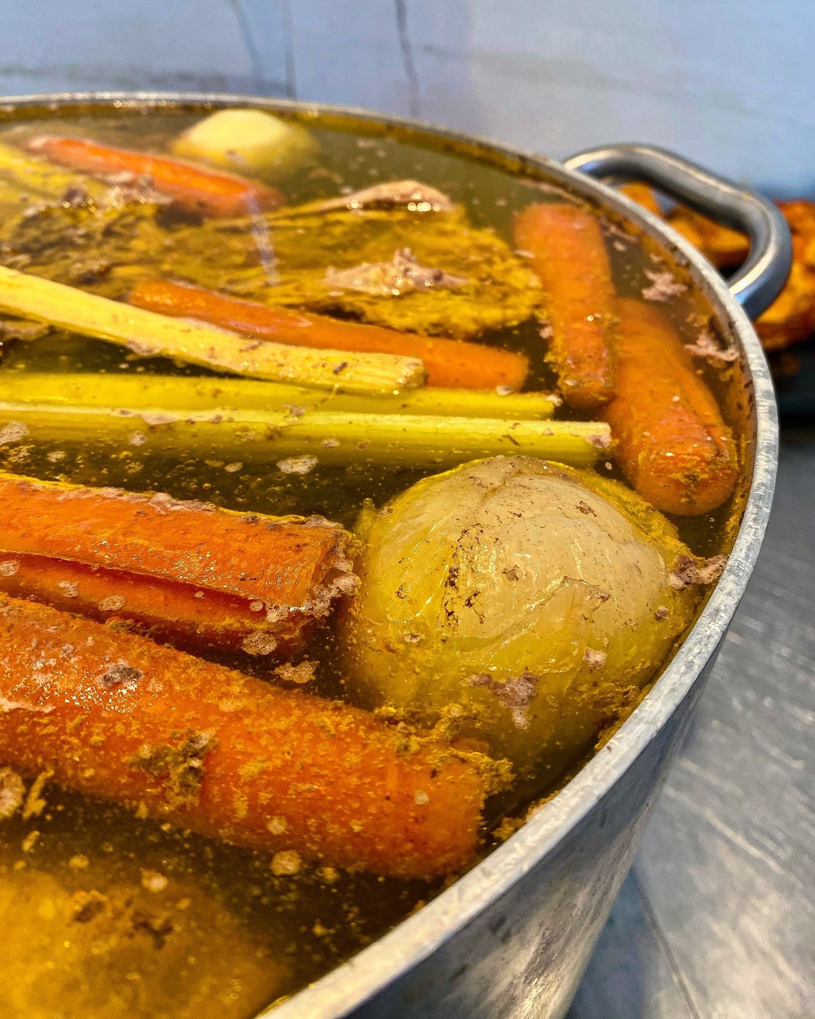 Pentola di zuppa di verdure con carote, sedano e una patata che sobbolle sul fornello
