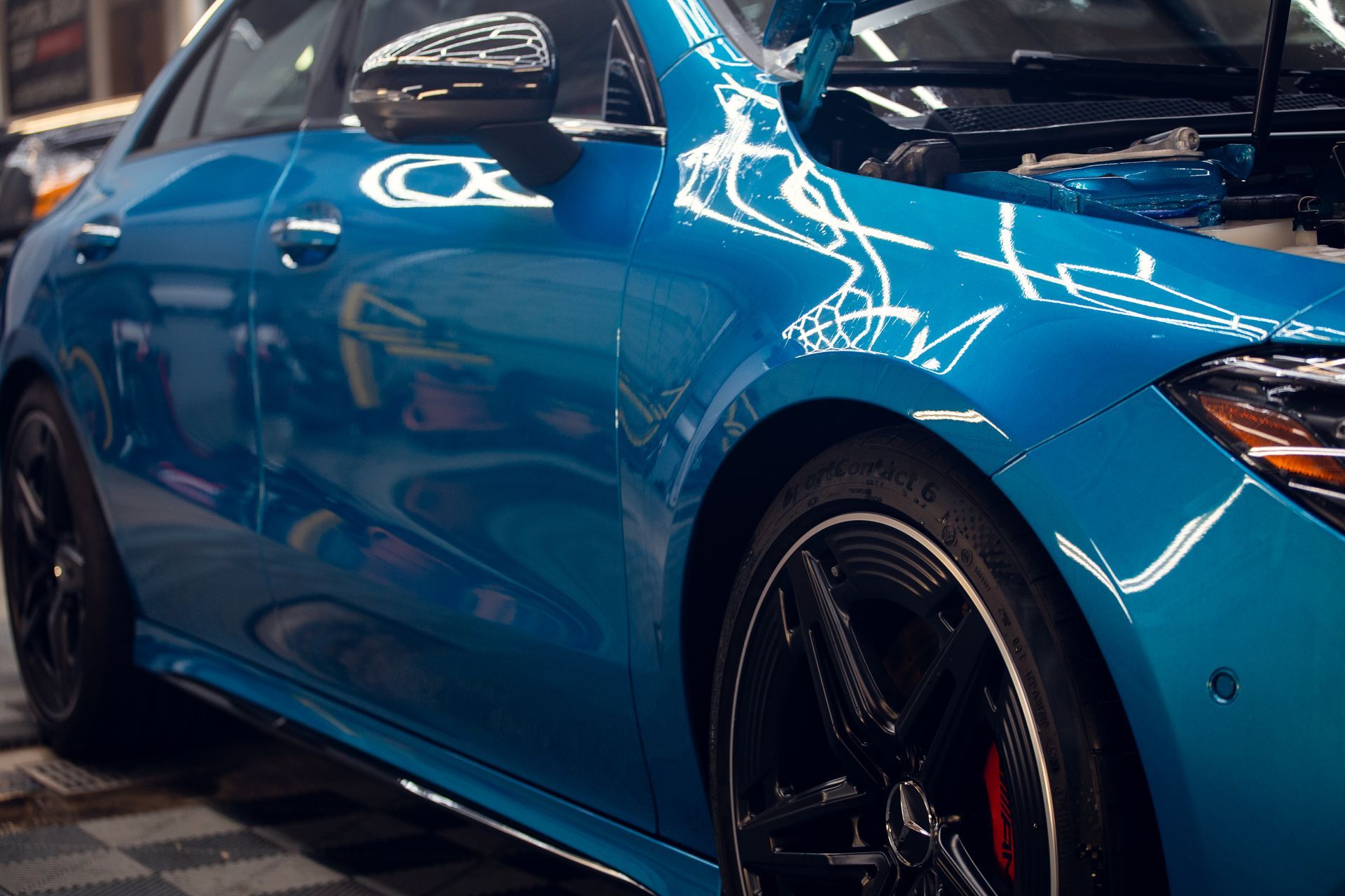 Blue sports car in a showroom, showing glossy side panels and black wheels