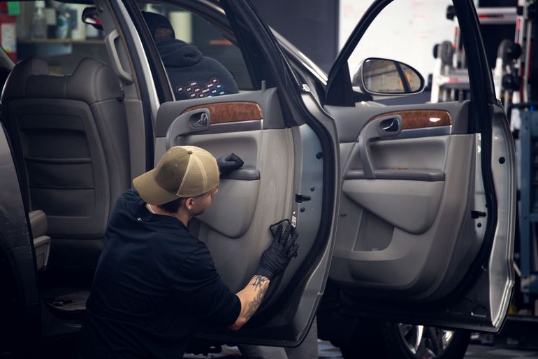 Mechanic working inside a car door panel in a garage workshop