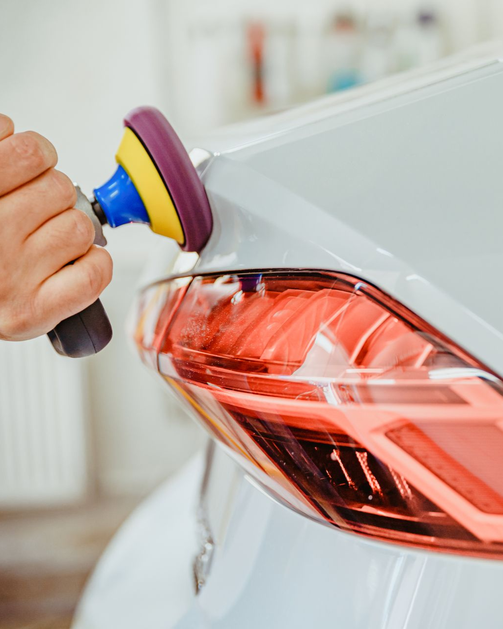 Hand polishing a car’s rear light with a buffing pad