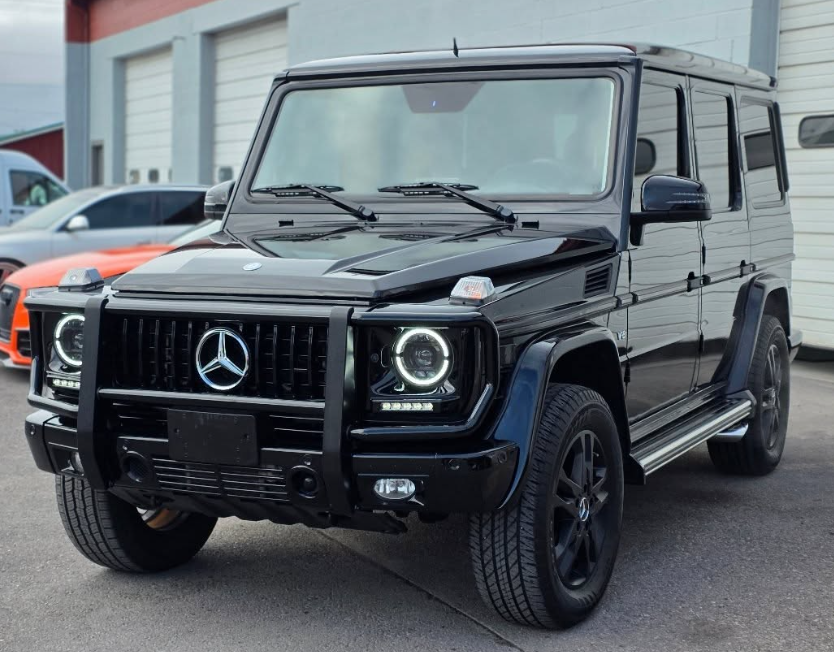 Black Mercedes-Benz G-Class SUV parked outside a building, front view.