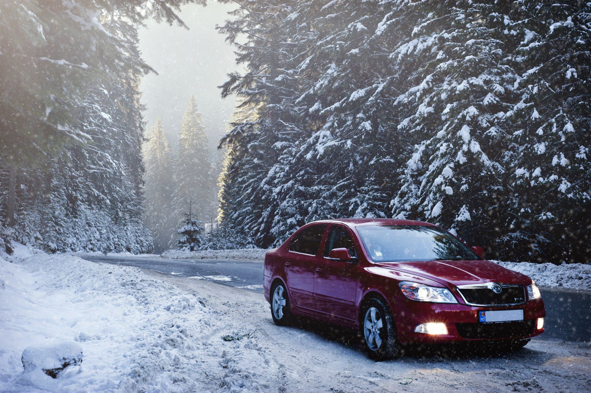 Red car driving on a snowy forest road