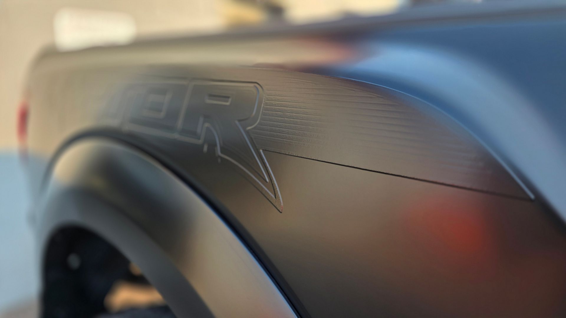 Close-up of a metallic black fender with embossed BR logo and a wheel in the background