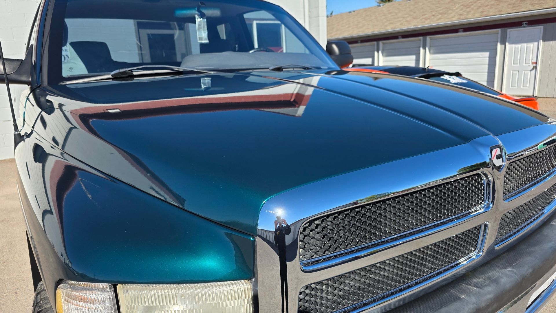 Shiny black Dodge Ram truck parked outdoors, front view with chrome grille and hood ornament.
