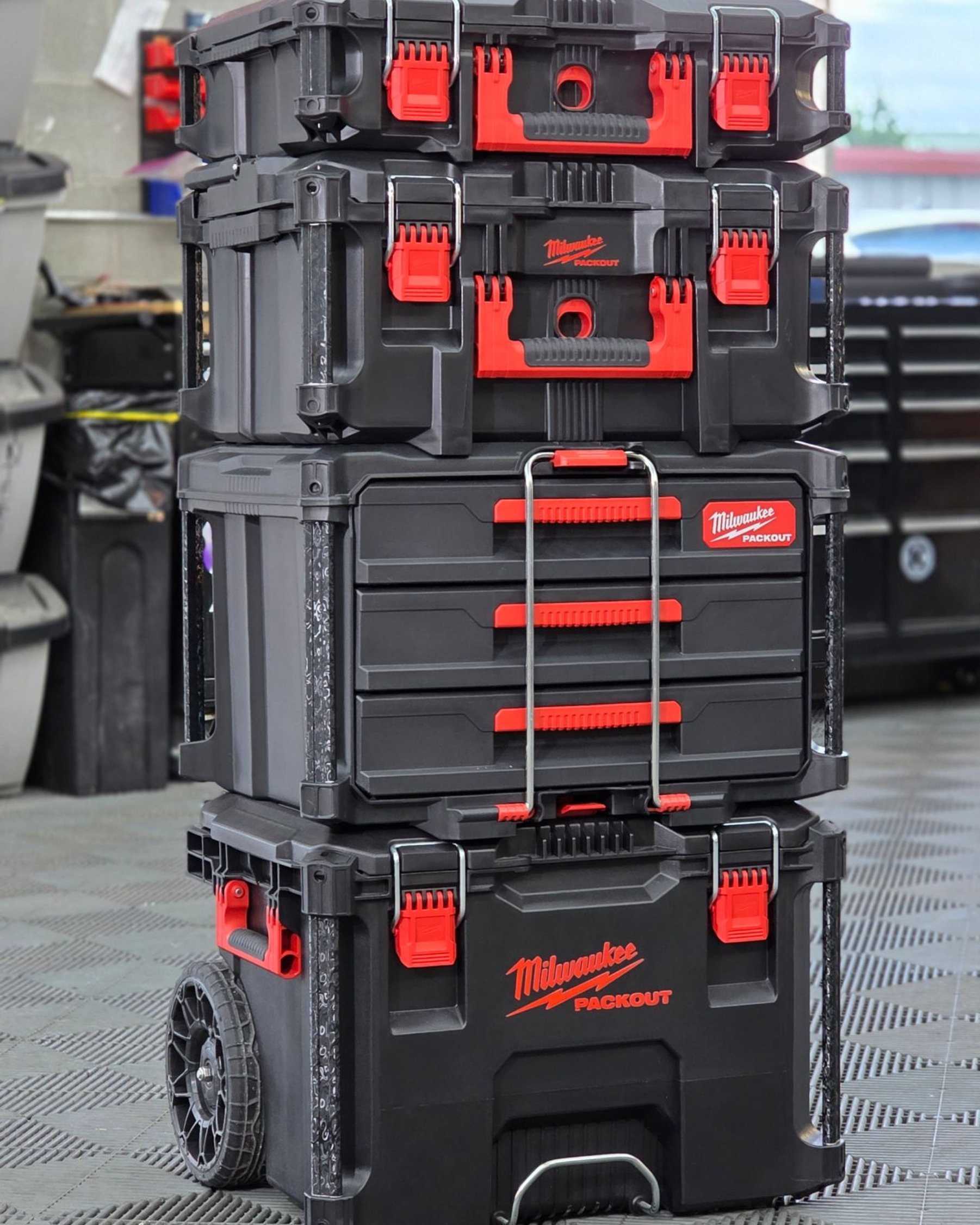 Stacked black and red Milwaukee tool boxes on a wheeled cart outdoors
