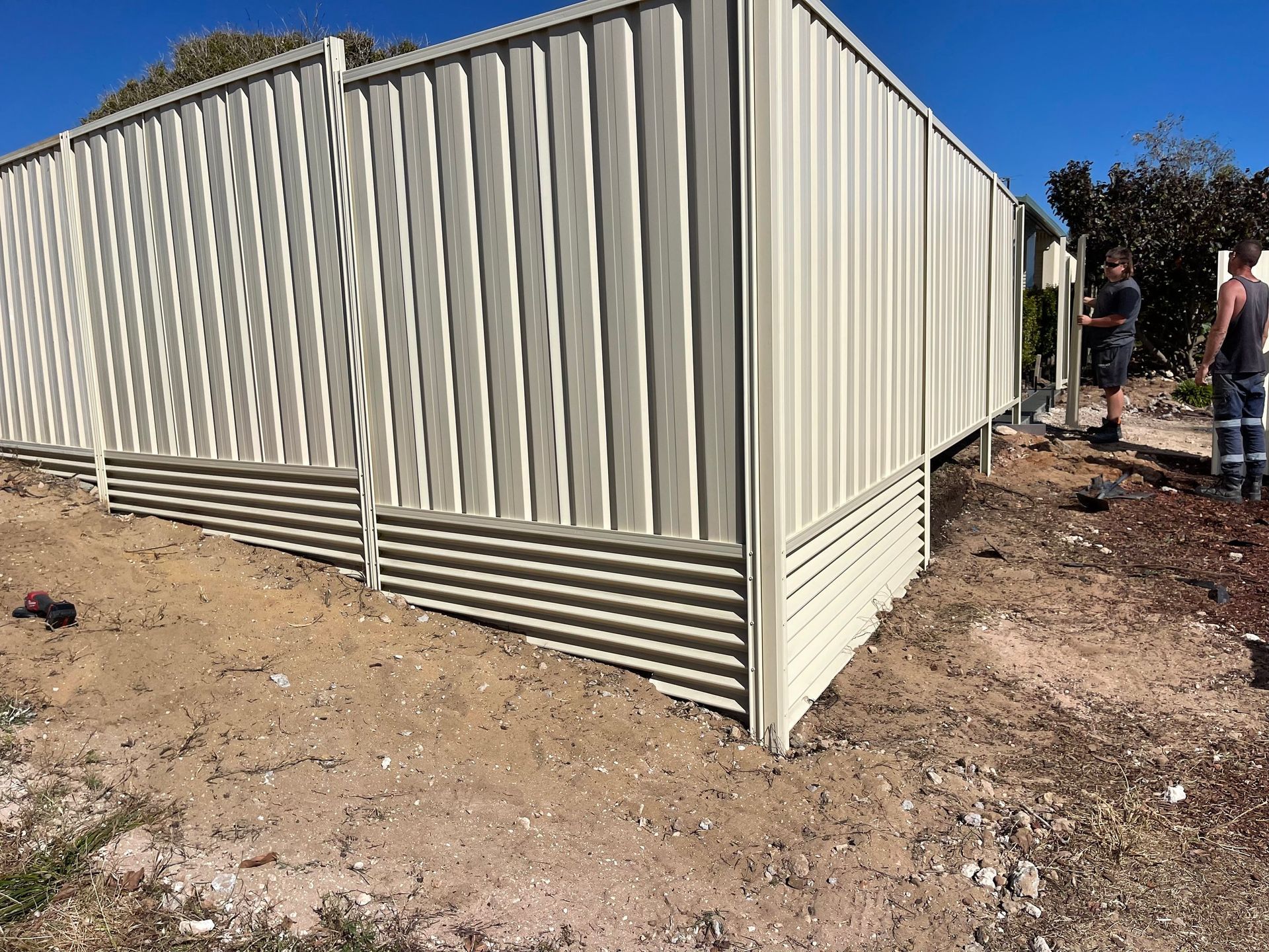 White corrugated metal shed on a dirt lot, with a person standing nearby on the right.