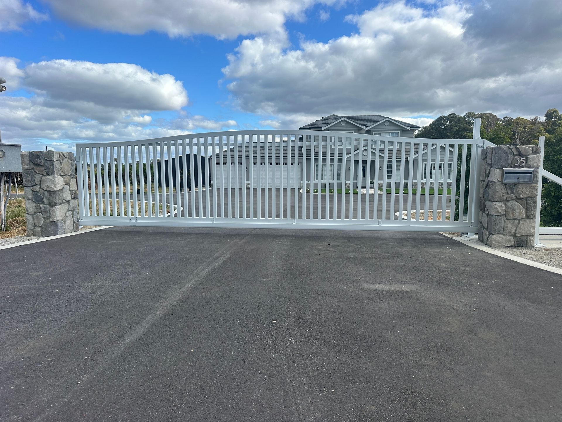 Dark gray horizontal slat fence along a paved sidewalk under a blue sky