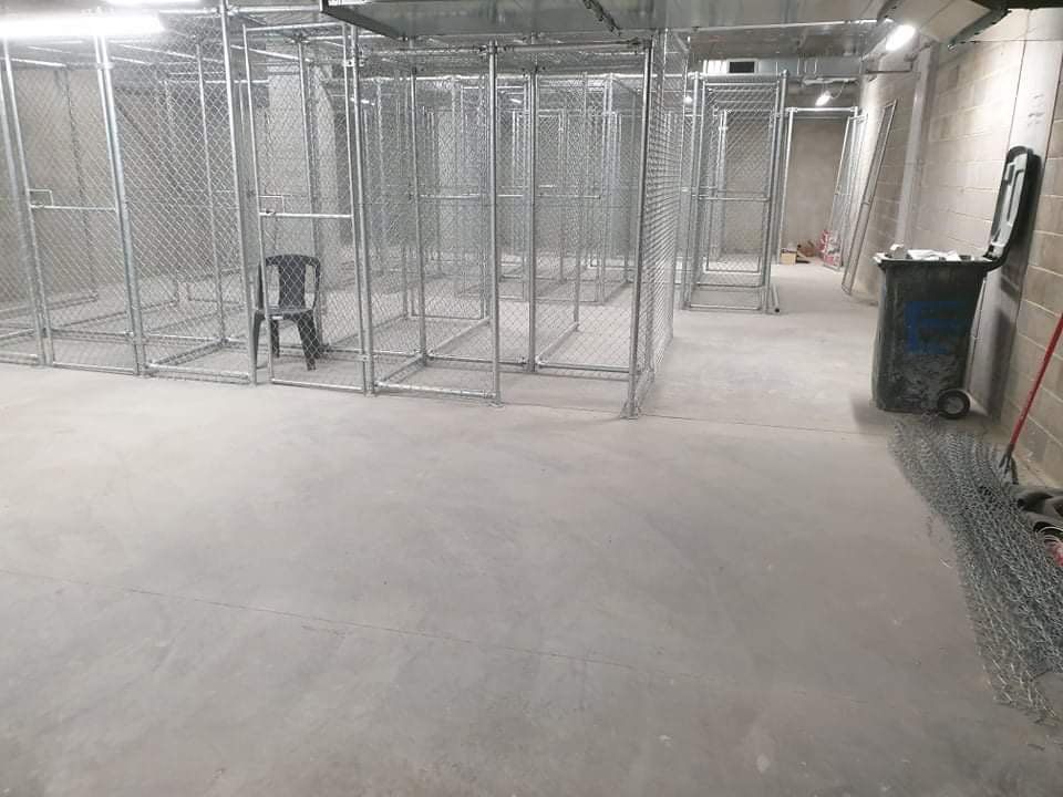 Empty industrial basement with chain-link cage rooms and concrete floor, under construction