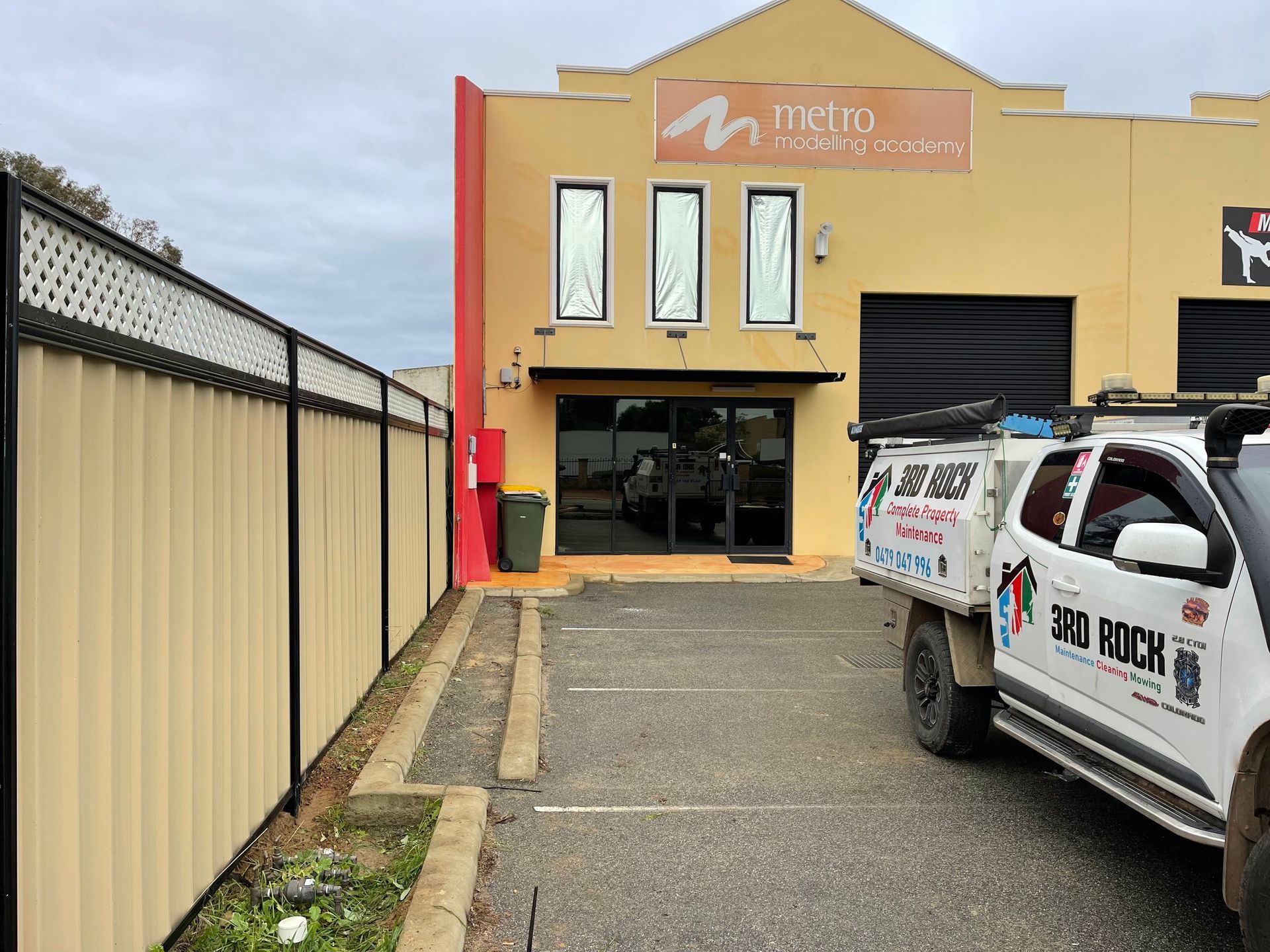 Commercial building entrance with parked utility van and fenced driveway