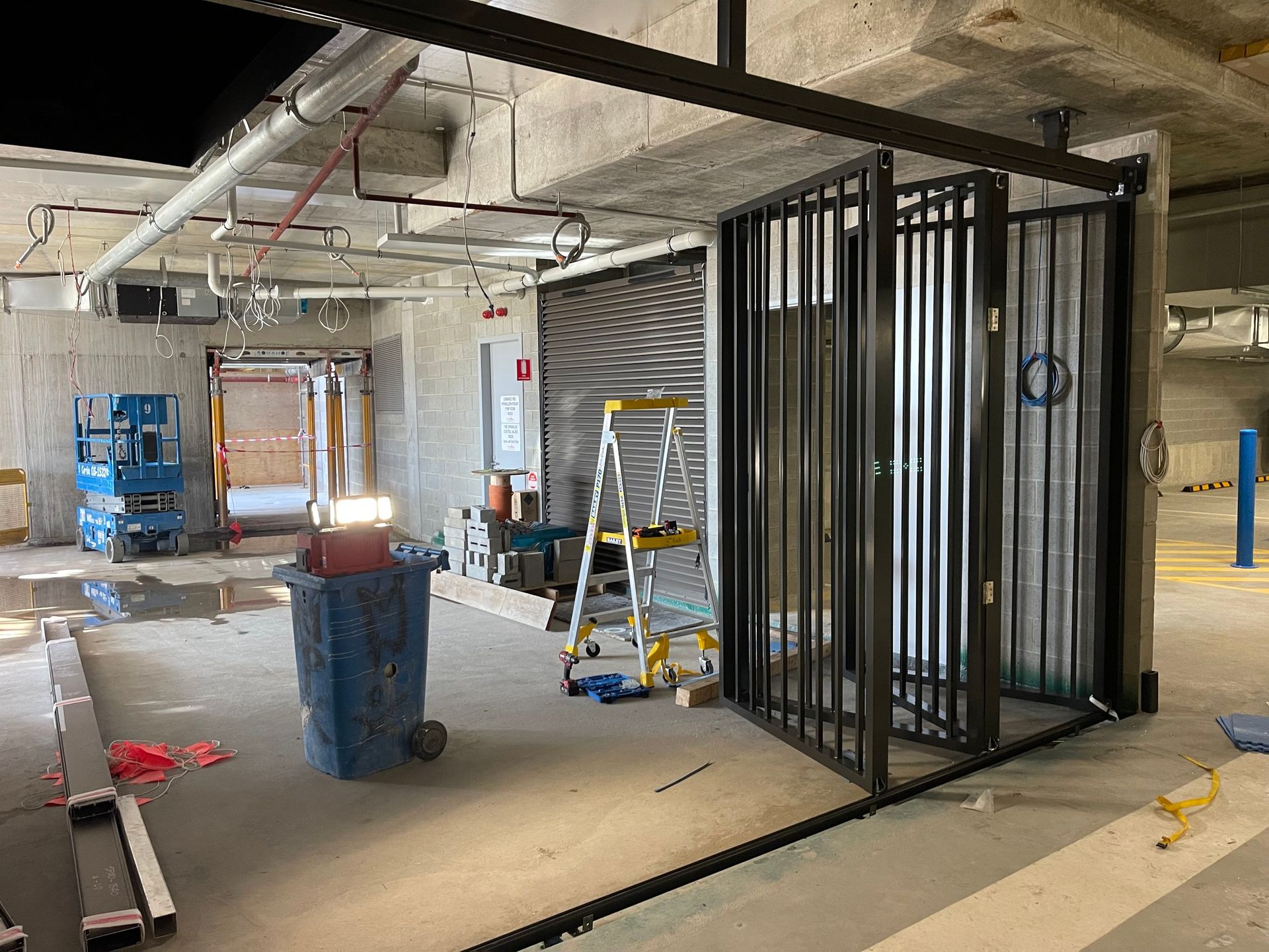 Partially built interior with concrete floor, metal framing, ladders, and construction equipment.
