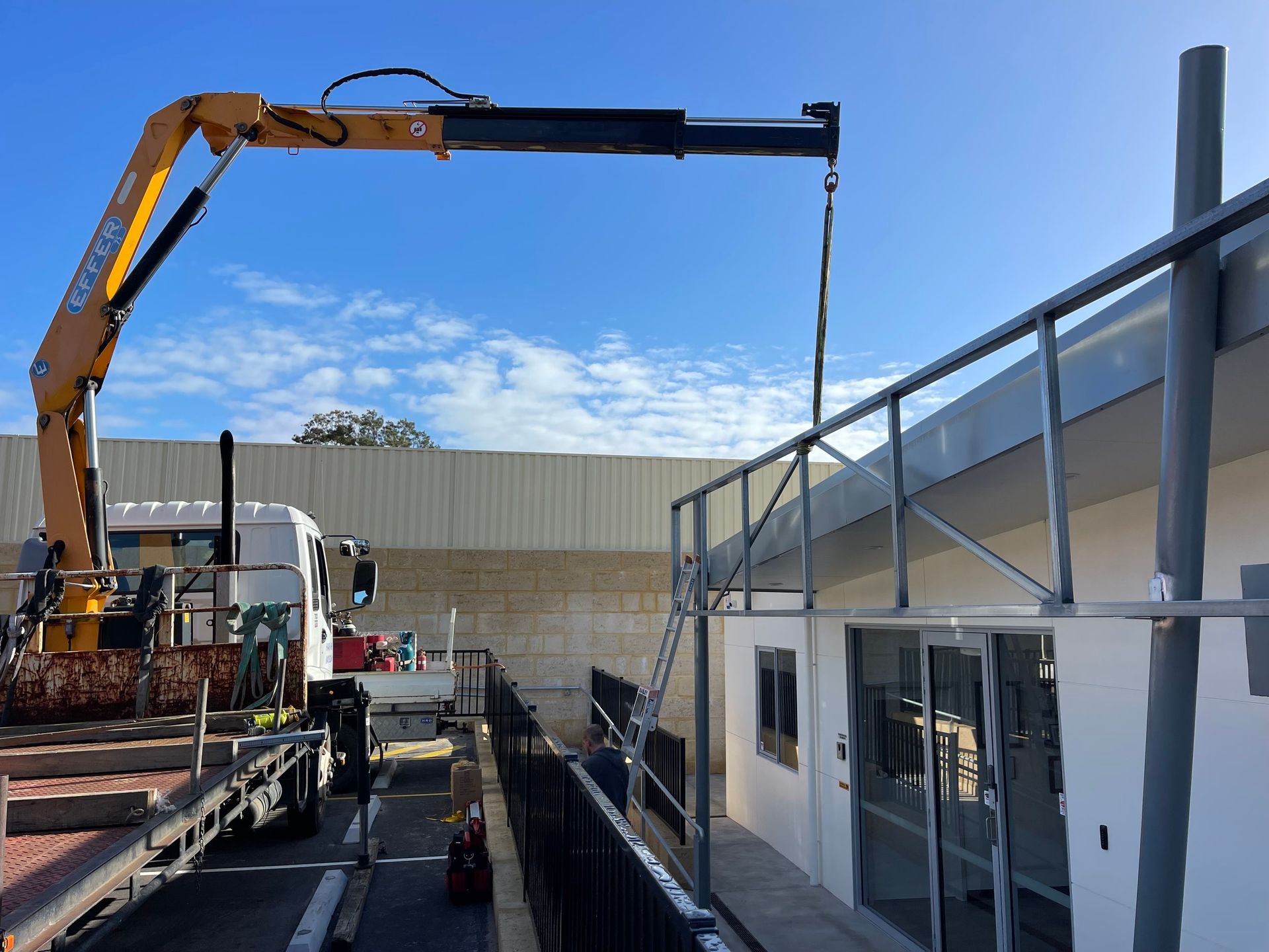 Crane lifting steel beams onto a building frame at a construction site.