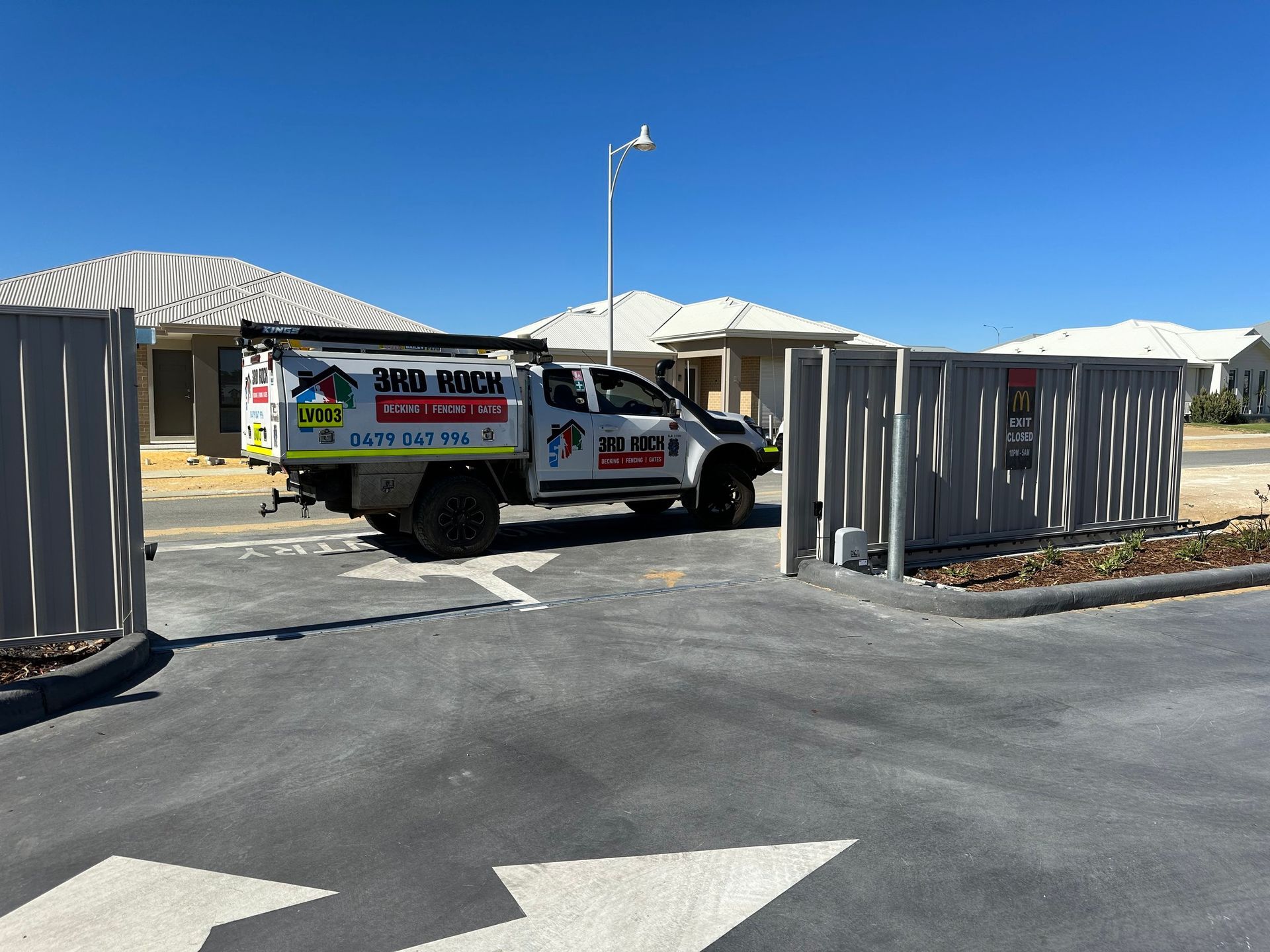 White utility truck at a gated entrance under a clear blue sky