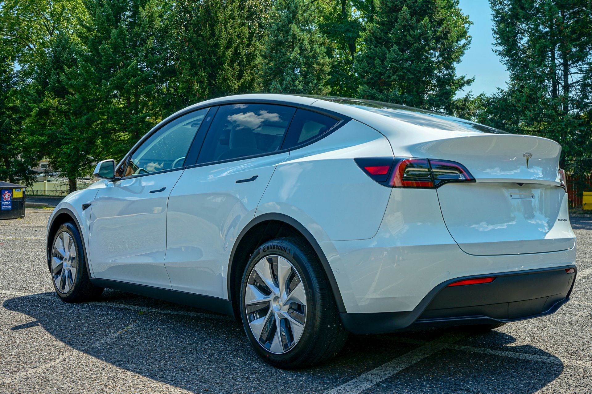 A white tesla model y is parked in a parking lot.