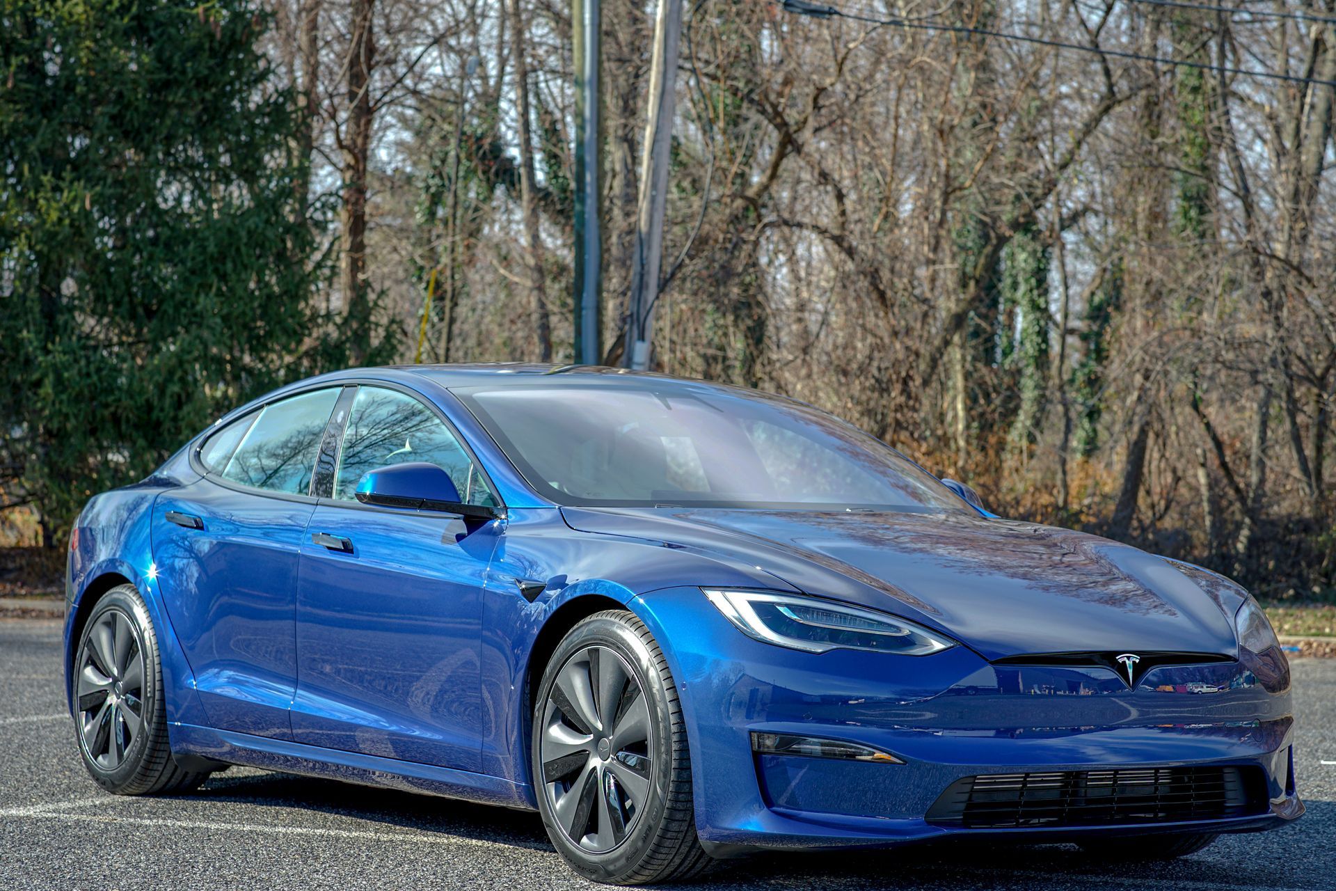 A blue tesla model s is parked in a parking lot.
